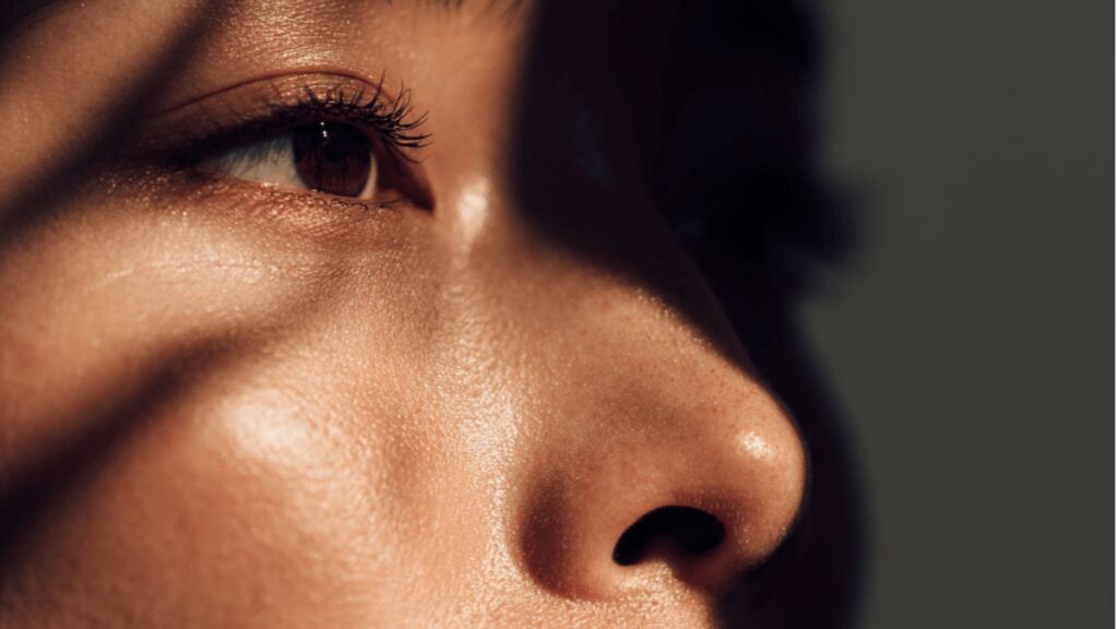 睡眠不足によりバリア機能が低下し、肌内部で慢性的な微弱炎症（炎症老化）が進行している女性の肌。影が強調され、疲れた印象を与えるイメージ。